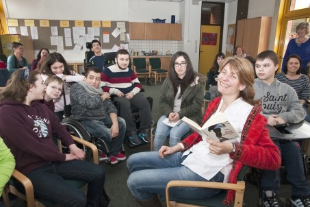 Die Kinder- und Jugendbuchautorin Kristina Dunker zusammen mit Schüler*innen und Schülern bei einer Lesung im Lehrer*innenzimmer.