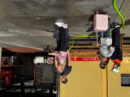 Eine Schülerin hat einen Feuerwehrschlauch in der Hand und löscht ein kleines Feuer.
